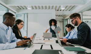 Fotografía de un equipo compuesto por tres mujeres y dos hombres de etnias diversas trabajando en una oficina