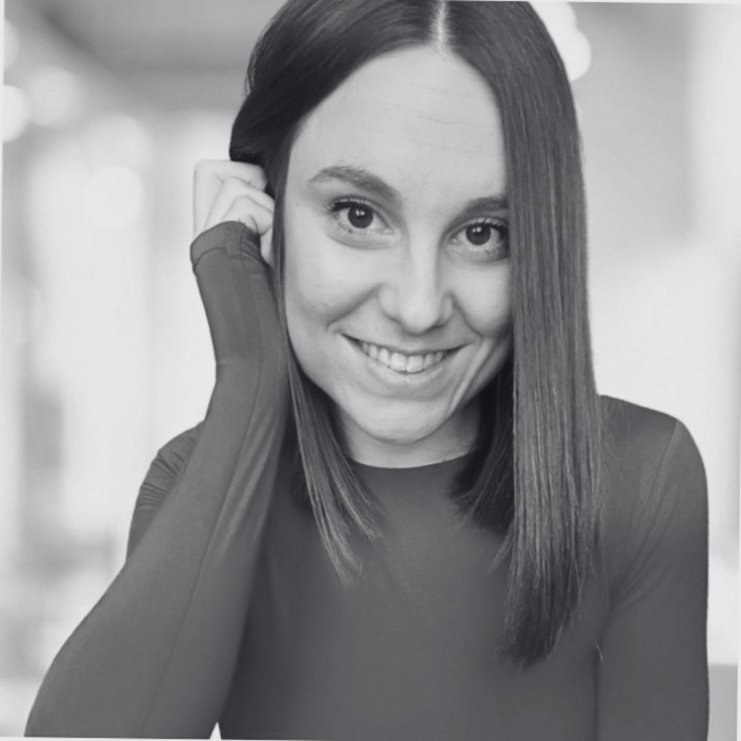 Persona sonriendo, pintada en blanco y negro, tocándose el cabello; fondo desenfocado. Ideal para campañas de marketing de cercanía y empatía.