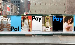 Fotografía de una calle con un muro bajo cubierto por carteles que muestran la nueva identidad de marca de PayPal
