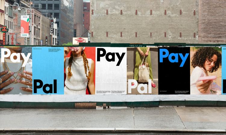 Fotografía de una calle con un muro bajo cubierto por carteles que muestran la nueva identidad de marca de PayPal